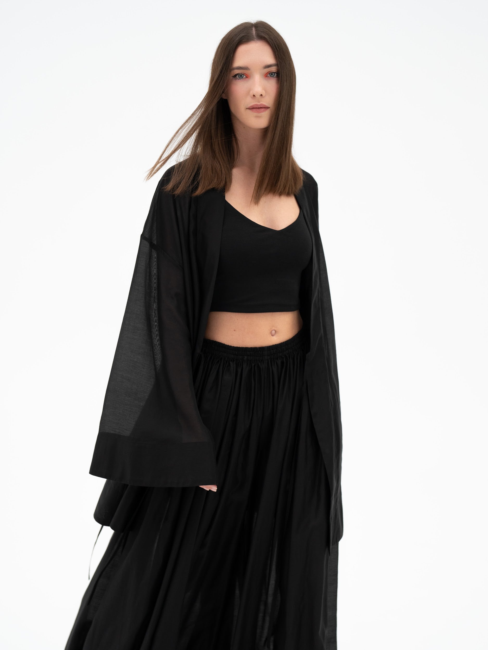 Woman wearing a black outfit with a flowing garment on a white background