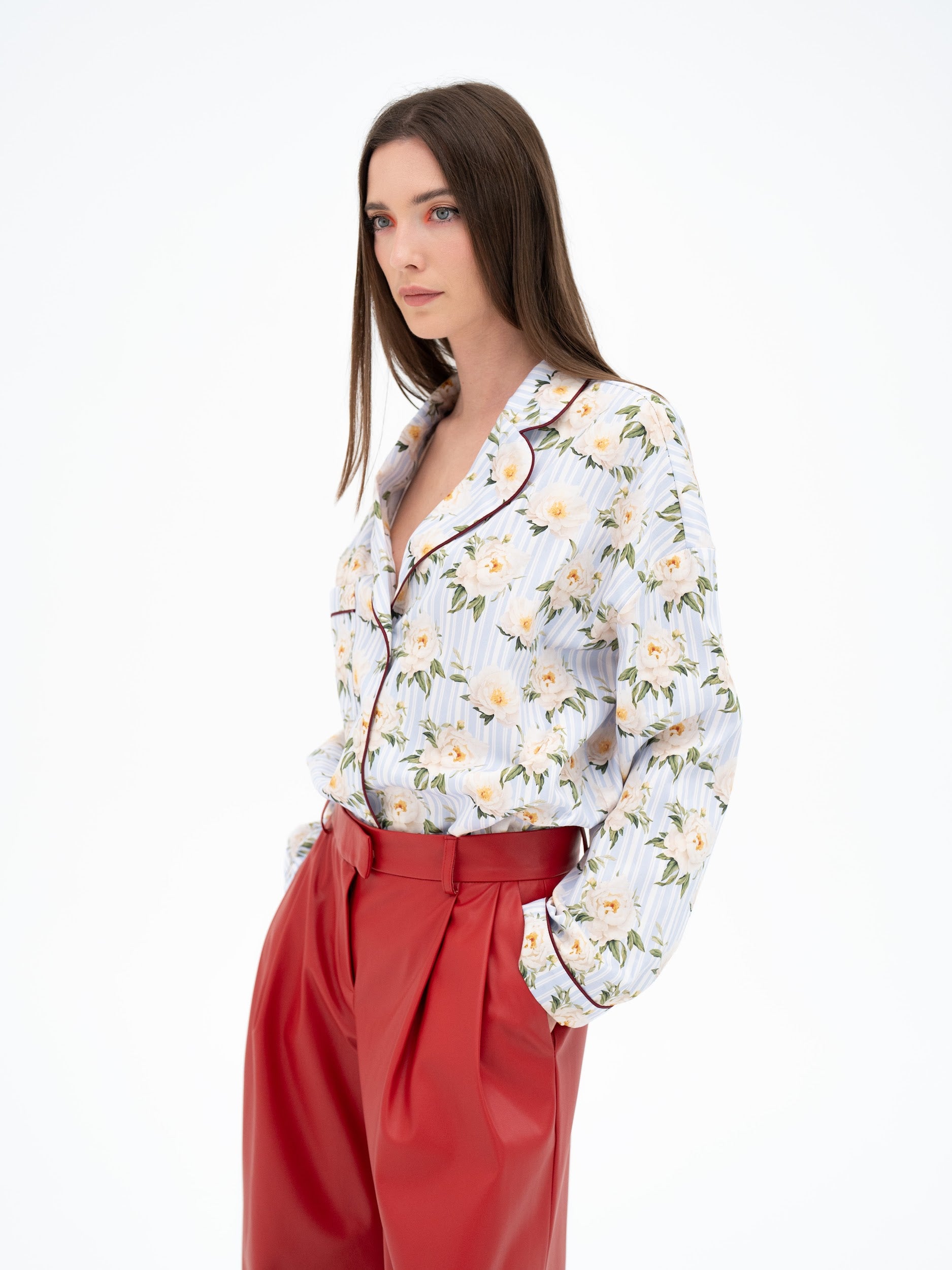 Woman wearing a floral blouse and red pants on a white background