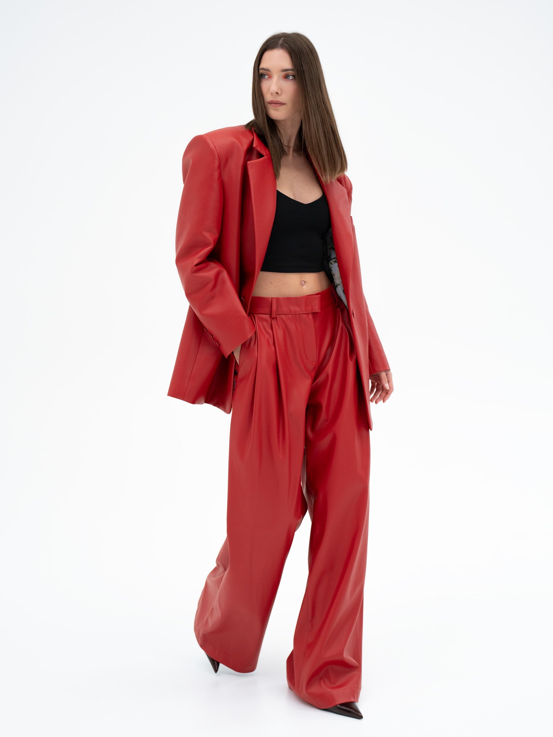 Woman wearing a red suit and black top on a white background